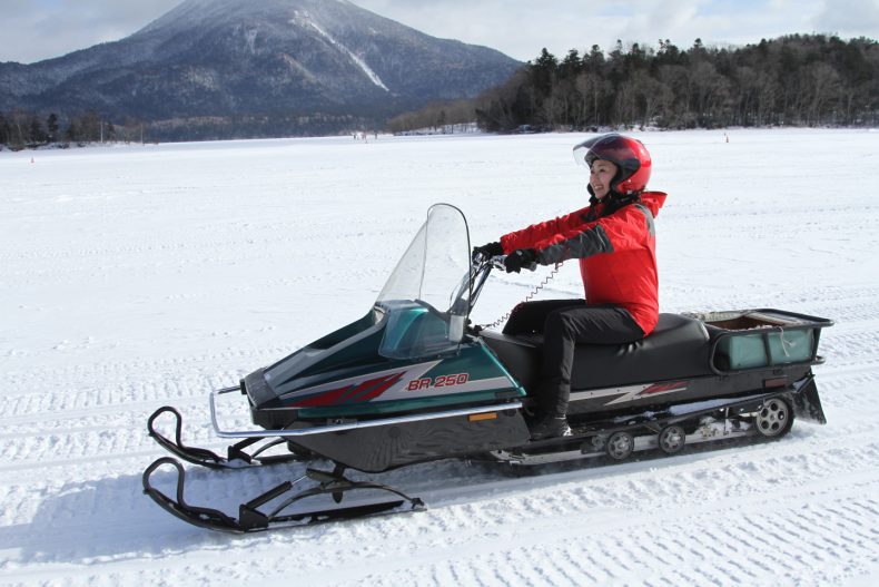 Close-up shot of steam rising from an onsen against a backdrop of snow-covered rocks and a dark blue, starry sky. Use a shallow depth of field to blur the background