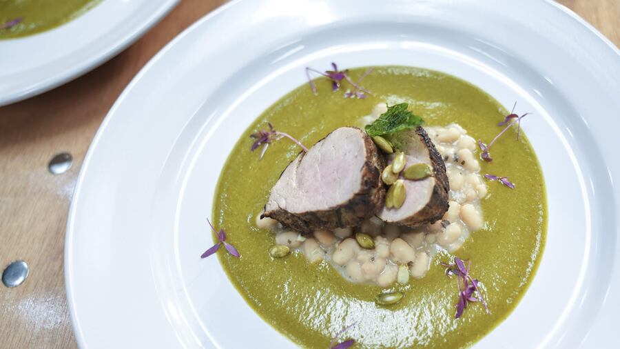 A close-up shot of Mole Negro simmering in an olla de barro over a traditional stove, showcasing the slow-cooking process.