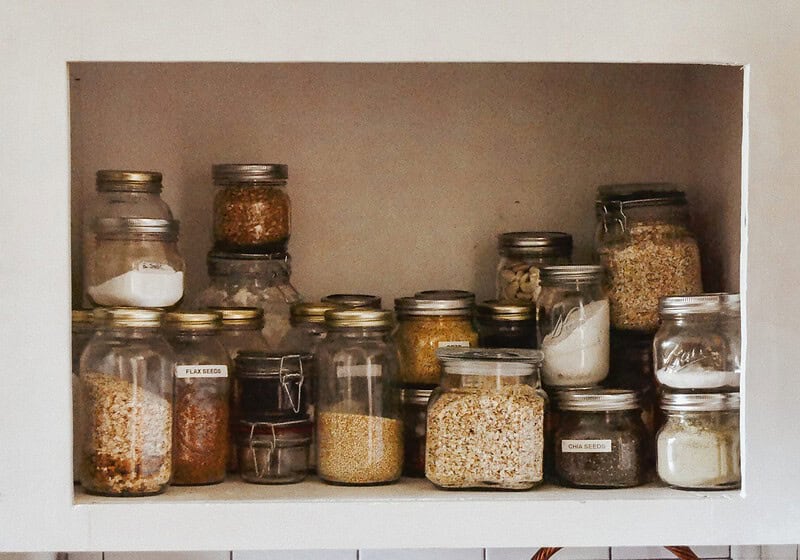 Pantry with neatly organized jars, featuring dried goods and canned foods on wooden shelves.
