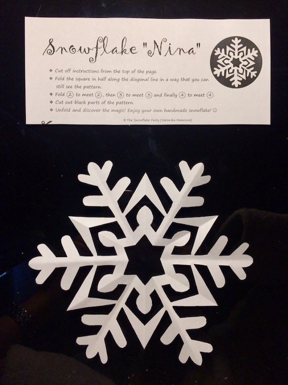 A shot of a snowflake partially unfolded, revealing some of the intricate cuts made with the scissors, hinting at the final design.