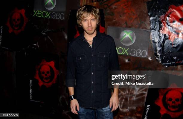Cliff Bleszinski wearing his signature backwards baseball cap, looking thoughtfully at a computer screen, embodying his role as an advocate for creative vision in the gaming industry.