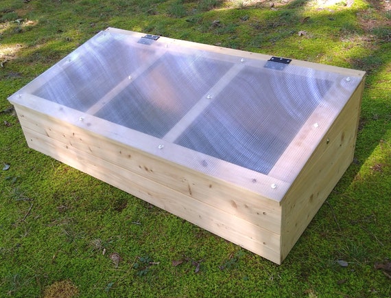 A cozy farmhouse with a cold frame in the backyard, symbolizing the blend of functionality and charm.