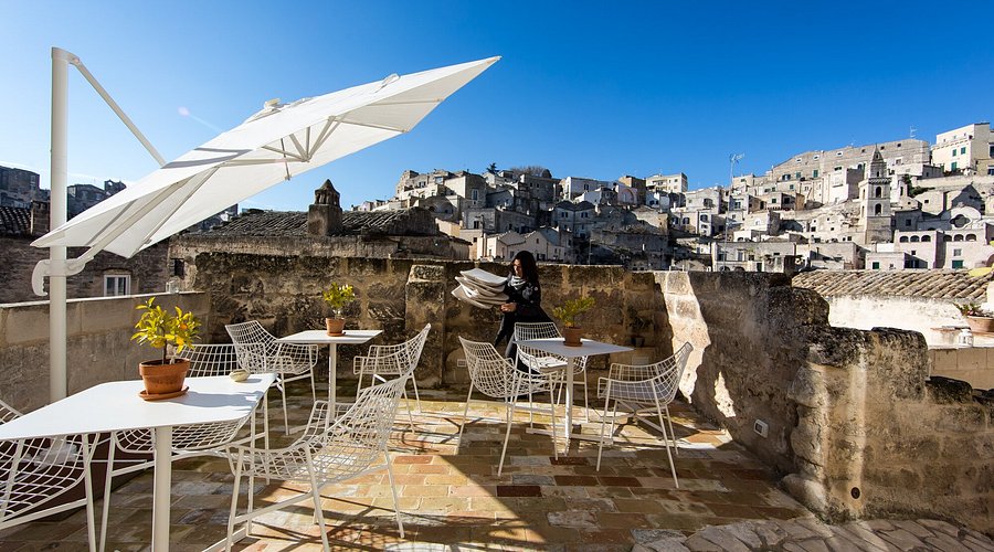Sofia holding a loaf of Pane di Matera in front of La Grotta Antica in Matera