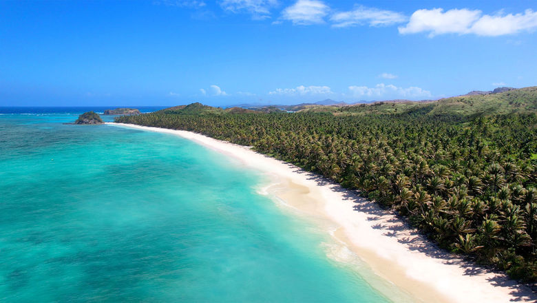 Panoramic view of a Yasawa Island with lush green vegetation, a pristine beach, and crystal-clear turquoise water, perfectly capturing the idyllic beauty of the islands.