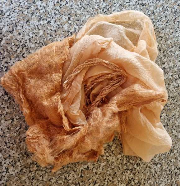 Fabric simmering in a dye bath inside a stainless steel dye pot