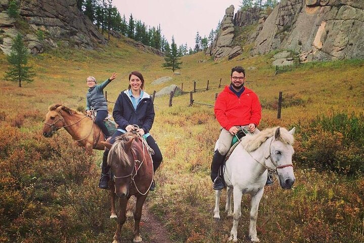 Anya riding a horse through Terelj National Park, with Turtle Rock visible in the distance.