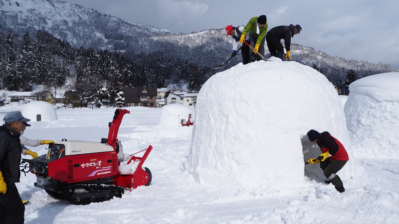 People sitting in a snow hut (Kamakura) with food, Iiyama, Nagano Japan