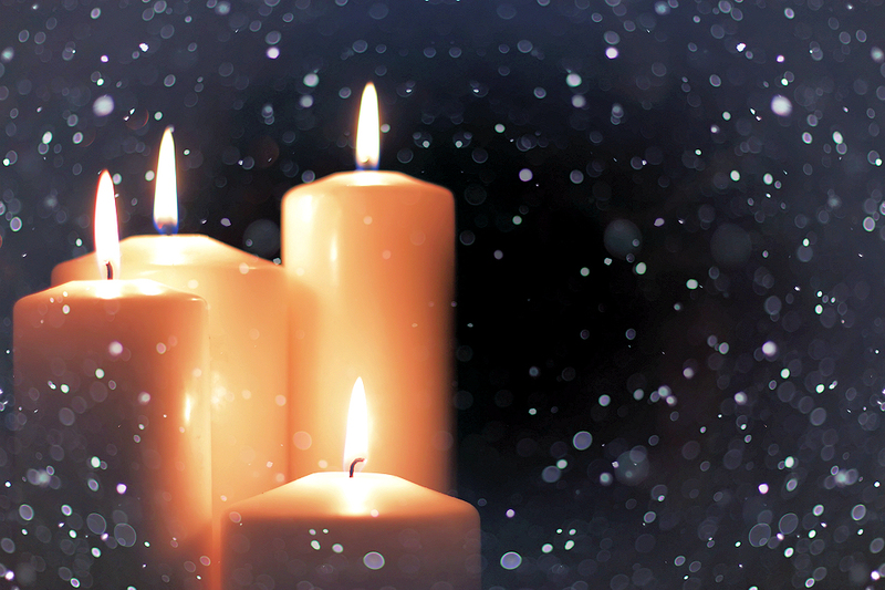 Close-up of a Yule Log centerpiece adorned with amethyst and clear quartz crystals, alongside traditional evergreen boughs and pinecones, on a dark wooden table.