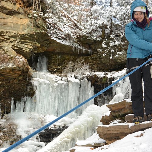 Winter Canyoning - Action shot of rappelling down frozen waterfall