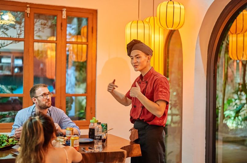 A bustling scene at Bún Chả Đắc Kim, showcasing its old-school Hanoi ambiance with simple tables and chairs spilling onto the street, where diners enjoy generous portions of charcoal-grilled pork.