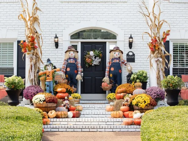 A beautifully decorated fall front porch with pumpkins, mums, and cozy blankets