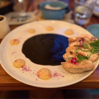 A perfectly plated mole negro dish at Criollo restaurant. The image should be a close-up, showcasing the rich, dark color and glistening texture of the mole, taken with soft, diffused light to emphasize the depth of color.