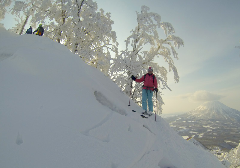 Helicopter flying over Mount Yotei during winter with a skier visible inside