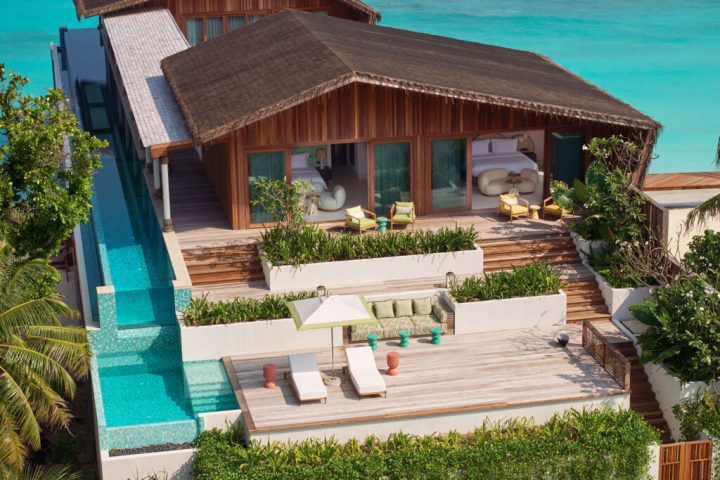 Overwater bungalow interior with a king-sized bed, ocean view, and woven textures