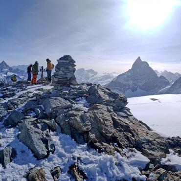 Panoramic view of the snow-covered Dolomites in winter, with the iconic Tre Cime di Lavaredo peaks dominating the landscape under a clear blue sky.