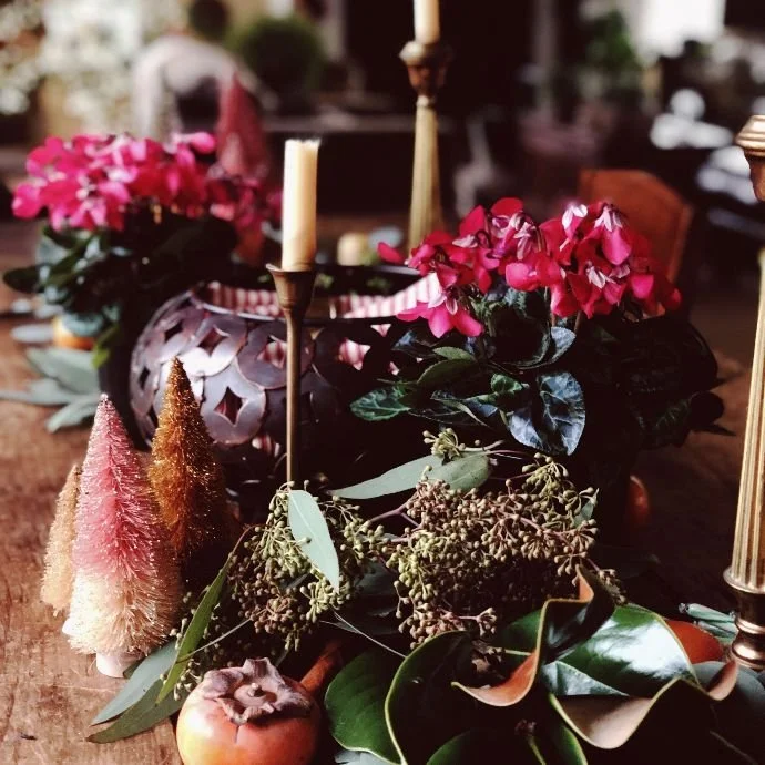 A beautifully set Thanksgiving table with spice-roasted pumpkin candles as the centerpiece, casting a warm glow on the surrounding dishes and decorations.