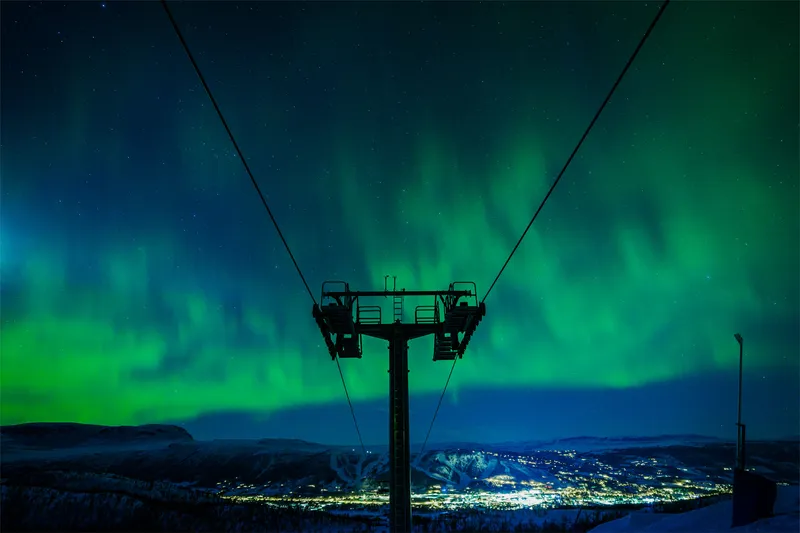 Brightly lit gondola against the dark Arctic sky, with views of Tromsø below