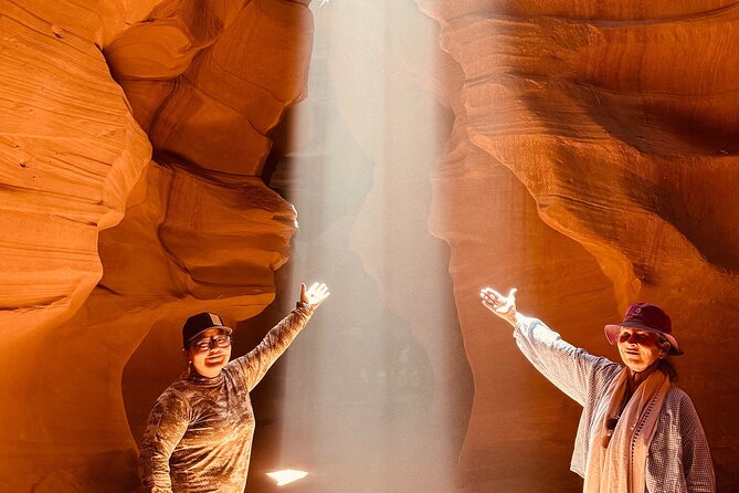 A musician plays a Native American flute within the narrow, sculpted sandstone walls of Antelope Canyon, Arizona, as beams of light filter through the opening above.