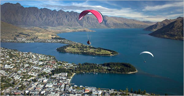 A person standing on Trolltunga, a rock formation in Norway, overlooking a stunning lake and mountain landscape. The image captures the breathtaking views and the adventurous spirit of the hike.