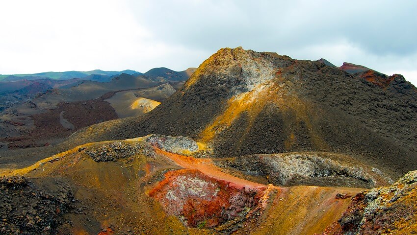A panoramic view of the Sierra Negra caldera, showcasing its vastness, volcanic terrain, and the dramatic contrast between the black lava fields and the surrounding landscape, highlighting the geological origins of the Galapagos.
