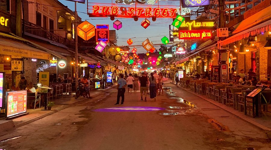 A dimly lit bar with a few patrons, evoking a sense of seediness and hidden activity.