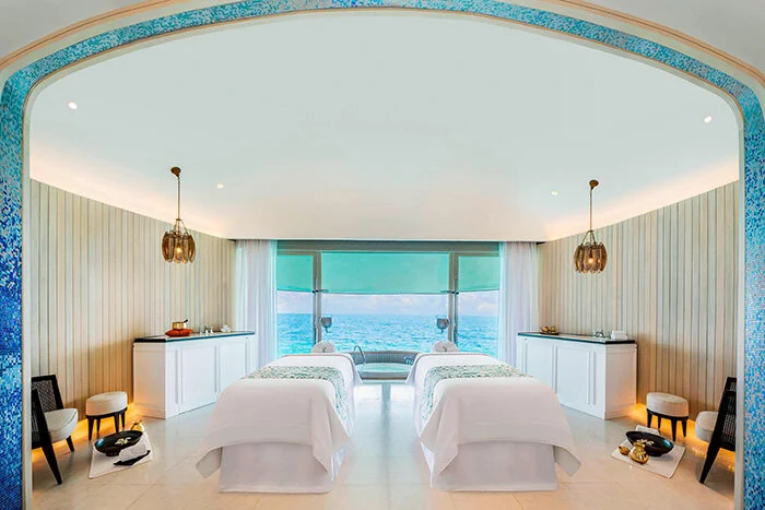 Interior of an overwater bungalow at the St. Regis Vommuli, showcasing luxurious furnishings and ocean views.