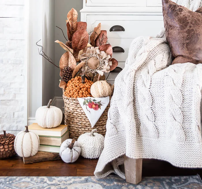 A farmhouse mantel with fall decorations and a basket filled with cozy blankets nearby, combining style and functionality.
