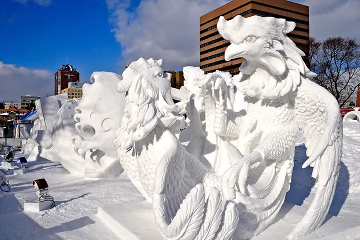 A close-up shot of an artist (preferably of Ainu descent) working on a detailed ice sculpture at the Sapporo Snow Festival, capturing the precision and artistry involved.