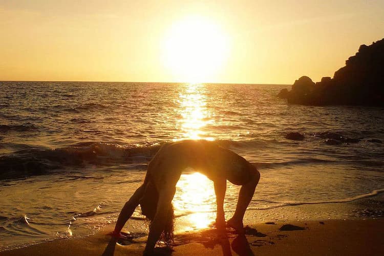 Hot Water Beach at sunset with silhouetted figures digging and steam rising, conveying a sense of quiet determination and earthy connection.