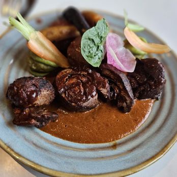 A close-up of Mole Negro being poured over chicken or enchiladas at Casa Oaxaca