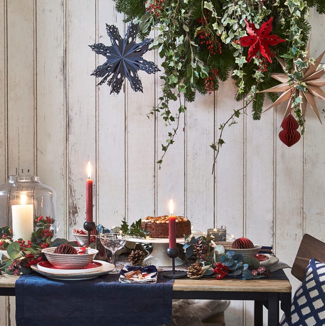 A cozy interior scene with a lit Christmas tree, warm lighting, and natural decorations, conveying a sense of slow living and holiday hygge