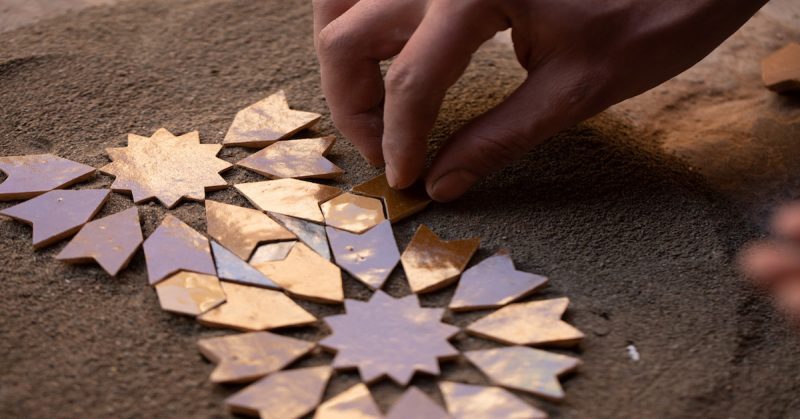 A baker carefully placing loaves of khobz bread into a traditional community oven, surrounded by intense heat and the yeasty aroma.