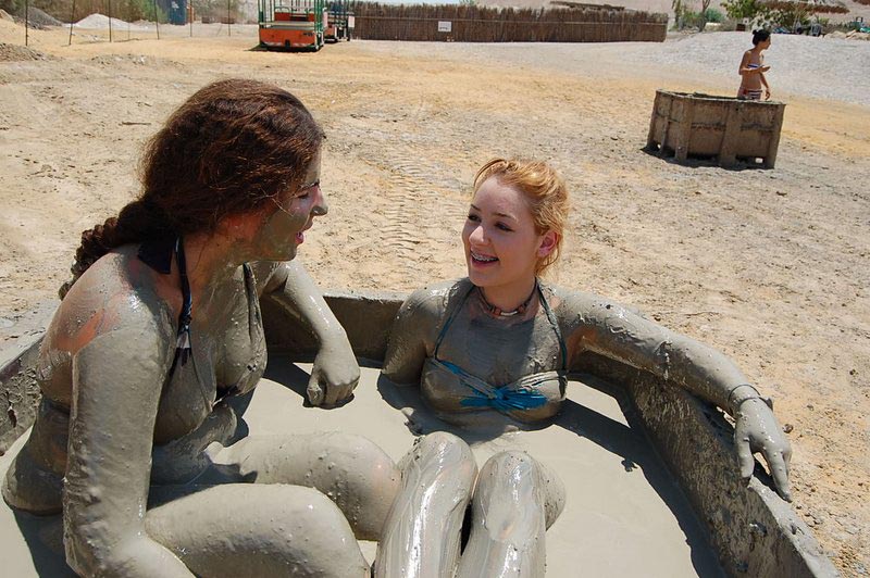 Person covered in Dead Sea mud smiling