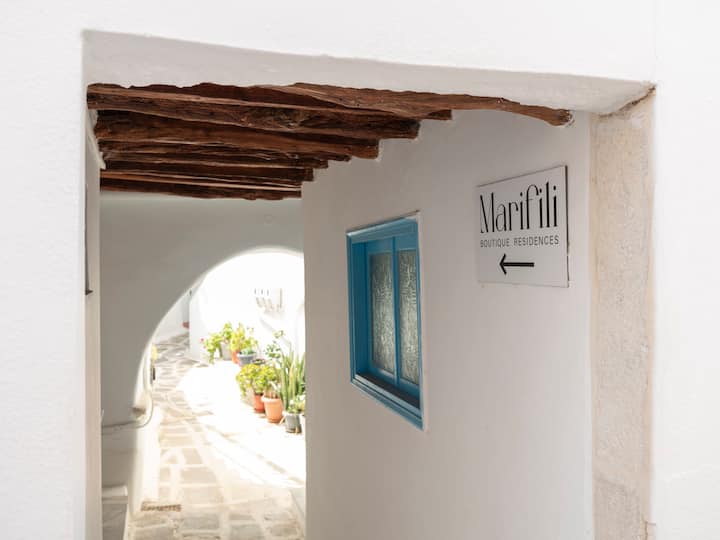 An interior shot of the Santorini cave house, showcasing the unique architecture, the play of light and shadow on the white-washed walls, the textured surfaces of the stone, and the minimalist design.