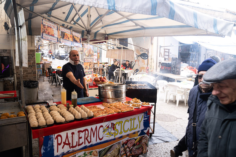 A vibrant photo of Ballarò Market filled with vendors and customers.