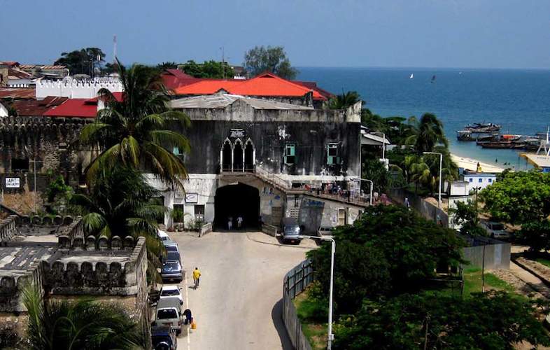A vibrant street scene in Stone Town with people, shops, and historic buildings