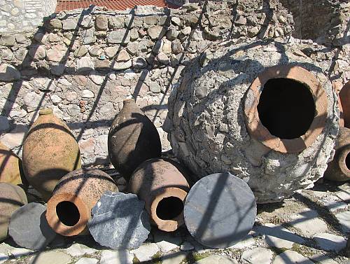 A winemaker carefully tastes wine directly from a Qvevri, illuminated by candlelight in the Kakheti wine region.