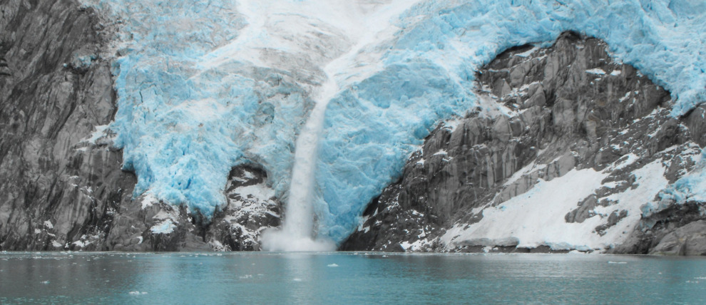 Exit Glacier in Kenai Fjords National Park, Alaska showing its receding state, with a ranger leading a guided hike on a gravel path, offering a stark visual lesson in climate change and its ecological implications.