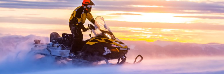 A Buryat shaman in traditional clothing during the Sagaalgan festival, holding a ceremonial instrument and with a blurred background of festival participants