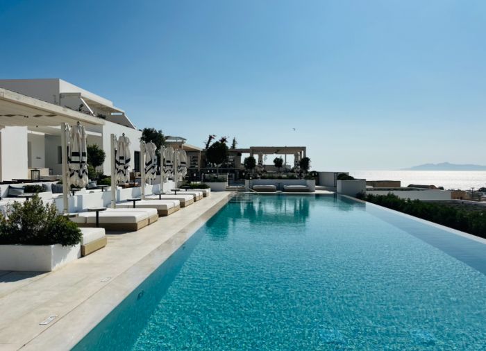 A stunning view of The Azure Boutique Hotel's infinity pool overlooking the caldera. The whitewashed walls and minimalist design create a sense of serenity and luxury.