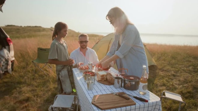 Wide shot of Whispering Pines Campsite, showing a family setting up their tent amidst tall pine trees.
