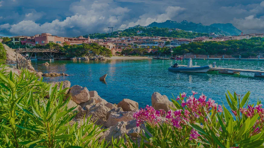 Turquoise water lapping against a pebble beach with the Julian Alps in the background