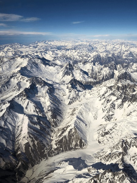 A lone hiker, silhouetted against a mountain vista, arms outstretched in joy, a sense of boundless possibility radiating from her.