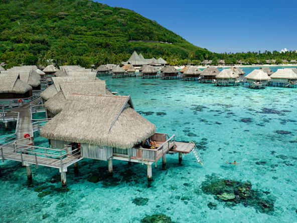 A view of Moorea's lush, green mountains rising dramatically from the turquoise sea, taken from a small airplane.