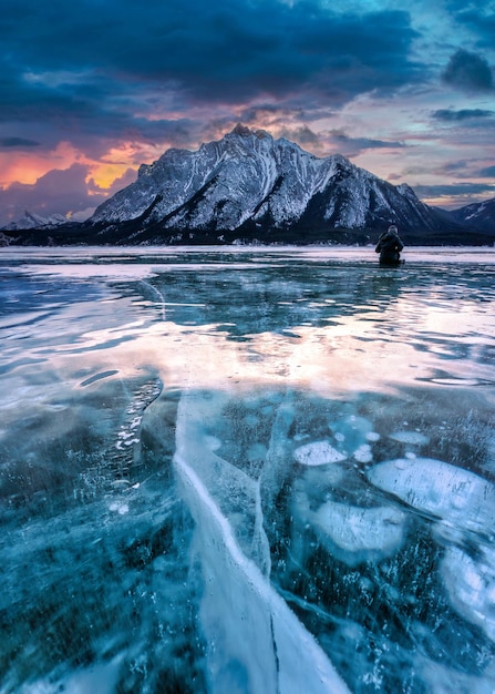 Action shot of a fat biker riding through a snowy forest trail, with sunlight filtering through the trees, creating dappled light patterns on the ground. Use a fast shutter speed (1/500th of a second or faster) to freeze the motion of the biker. Use a shallow depth of field (f/2.8-f/4) to blur the background and emphasize the biker. Capture the biker in a dynamic pose, leaning into a turn or climbing a small incline.