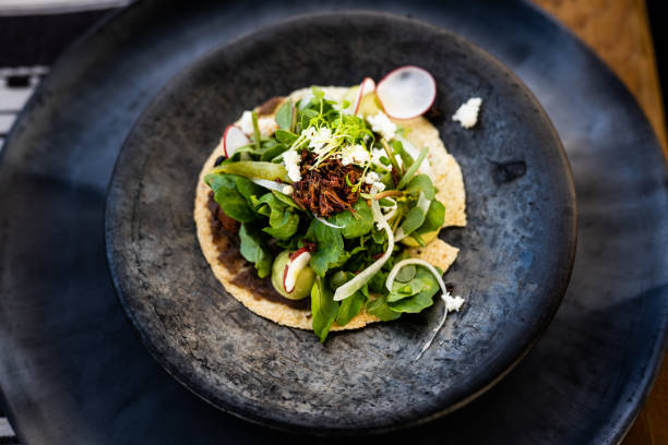 An overhead shot of a pre-hispanic mole tostada with chapulines and quelites showcases the unique ingredients and presentation of Oaxacan street food