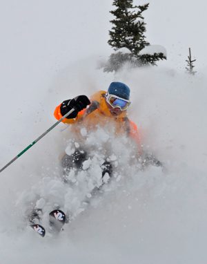 Heli-Skiing in British Columbia, Canada: A helicopter hovering over pristine, snow-covered mountains, with skiers preparing to carve through untouched powder.