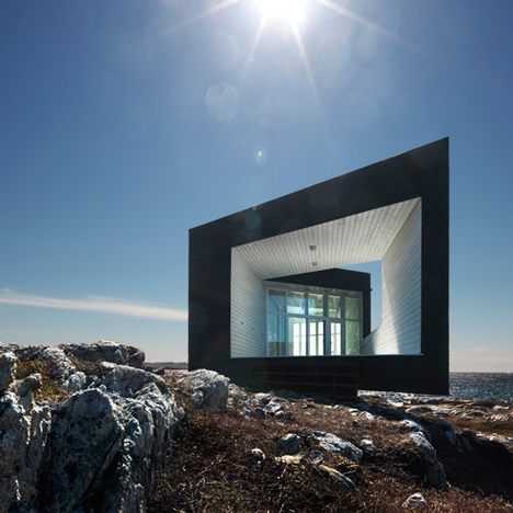 The stark white exterior of the Fogo Island Inn contrasts with the rocky coastline, highlighting its modern design while respecting the traditional landscape.