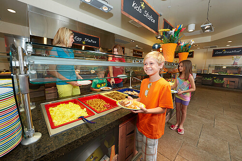 A toddler eating apple fries at Legoland, smiling with excitement.