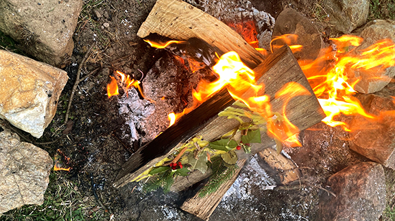 Hands demonstrating the process of wrapping a Winter Solstice herb bundle with twine.